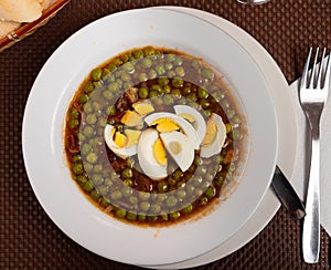 Guisantes a la Murciana - Peas Murcia Style. Juicy peas sauteed with cured ham served with boiled egg on plate, popular photo