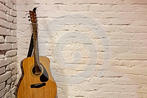 Guitar against white background. Acoustic musical instruments stands leaning on brick wall with empty copy space to add text of