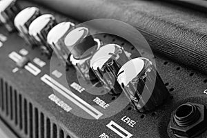 Guitar amplifier macro photography. Control knobs. Electric playing equipment. Black and white picture.