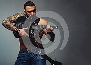 Guitar as weapon. Brutal latino man playing the broken guitar. Hispanic guitarist performing music on electric guitar