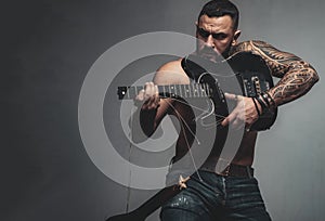 Guitar as weapon. Brutal latino man playing the broken guitar. Hispanic guitarist performing music on electric guitar
