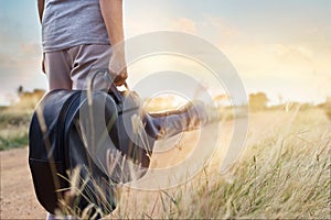 Guitar bag in hand on countryside road in nature background