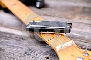 Guitar with blues harmonica on wooden ground