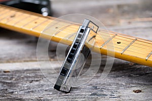 Guitar with blues harmonica on wooden ground