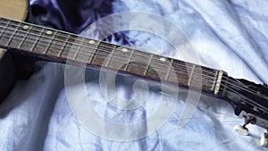 Guitar with broken string resting on the bed