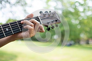 guitar chord played outdoors in a park with trees as background