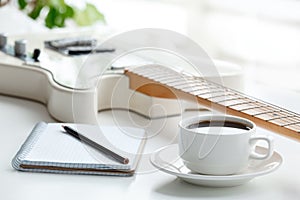 Guitar, coffee, notepad and pencil.