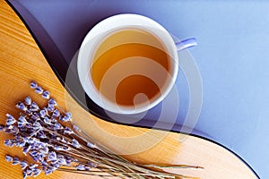 Guitar deck with dried lavender flowers and cup of herbal tea, closeup, top view.