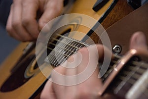 Guitar deck and guitarist hands closeup. Capo on the fretboard of a guitar. Blurred guitar background