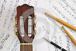 Guitar, drum sticks with pen on music score