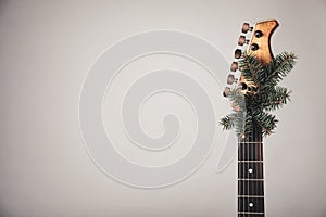 Guitar with fir tree branch on light background, space for text. Christmas music