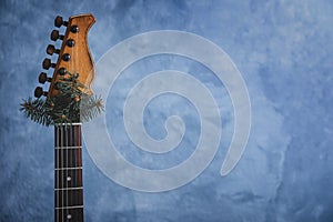 Guitar with fir tree branch on light blue background, space for text. Christmas music