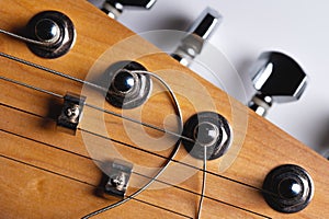 Guitar fretboard with tuning pegs and strings on a gray background. Close-up