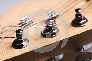 Guitar fretboard with tuning pegs and strings on a gray background. Close-up