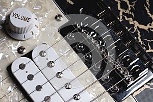 Guitar fretboard with tuning pegs and strings on a gray background. Close-up