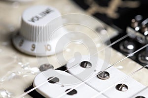 Guitar fretboard with tuning pegs and strings on a gray background. Close-up