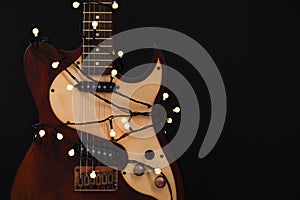 Guitar with golden lights on black background. Christmas music