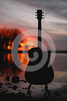 Guitar by the lake at sunset time