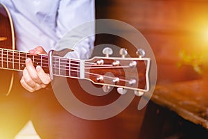 Guitar with a man`s male hands playing the guitar on wooden wall background, electric or acoustic guitar with nature light. Concep