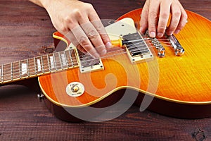 Guitar master adjusts intonation on electric guitar at workplace