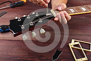 Guitar master adjusts the trussrod on electric guitar at workplace