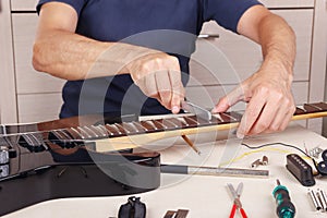 Guitar master crowning frets on electric guitar neck with fret files