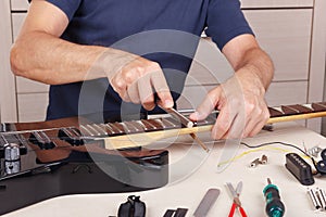 Guitar master crowning frets on guitar neck with fret files