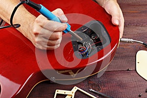 Guitar master soldering electric guitar wiring in workplace