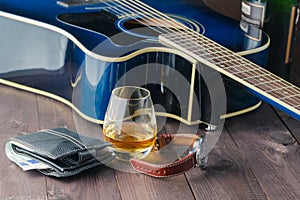 Guitar, money and whiskey on wooden table