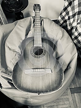 Guitar. A musical instrument rests on a soft ottoman.