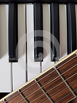 Guitar neck, with its frets and strings, over a piano keyboard being shown together