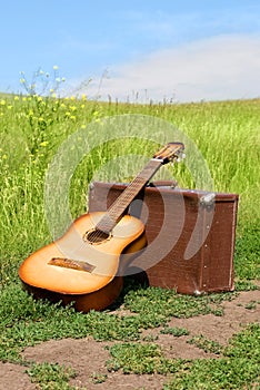 Guitar and old leathern suitcase on the road