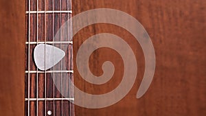 Guitar pick on wooden guitar neck on the frets of the guitar on wooden background photo