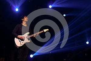 Guitar player in action on stage with colorful glow bright spotlights and smoke on rock stage concert in dark background, stage