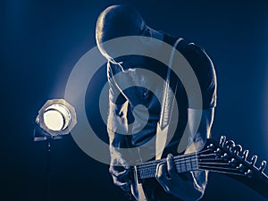 Guitar player in front of spotlight blue tone