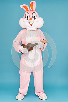 Guitar player or guitarist is playing music by ukulele. Easter bunny or rabbit or hare celebrates Happy easter, dancing
