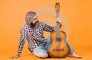 Guitar player on yellow background. Cheerful guitarist. charismatic mature man playing guitar while sitting. relax with