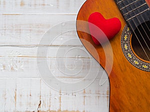 The guitar and red heart on white wooden texture background. Love, Music day concept.