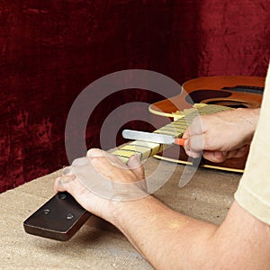 Guitar repair and service - Worker sharpen special tool bridge servo nut black acoustic guitar