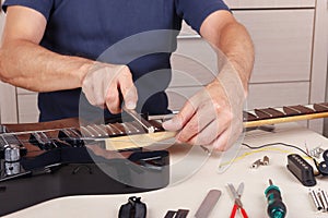 Guitar repairer crowning frets on guitar neck with fret files