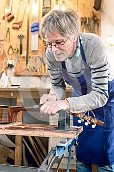 Guitar repairer filing the frets of an acoustic guitar