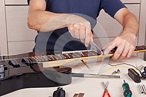 Guitar repairman crowning frets on guitar neck with fret files