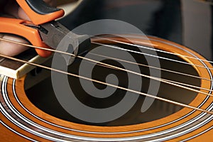 Guitar restring: musician cut strings from an acoustic guitar photo