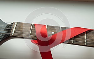 Guitar, rock music and red ribbon - symbol of fight against AIDS