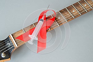 Guitar, rock music, a syringe and red ribbon - symbol of fight against AIDS