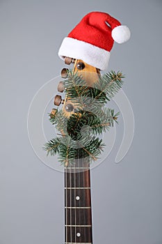 Guitar with Santa hat and fir tree branch on background. Christmas music
