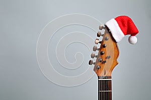 Guitar with Santa hat on grey background. Christmas music