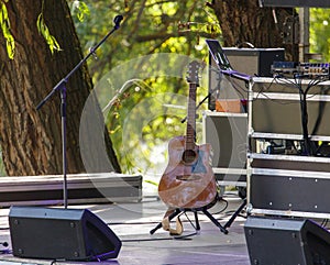 A guitar is sitting on a stand in front of a microphone