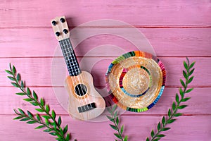 Guitar and sombrero hat on pink background. Stereotypical attributes of Mexican culture.