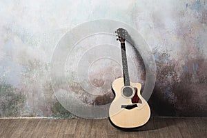 The guitar stands near the wall in the style of grunge, music, musician, hobby, lifestyle, hobby